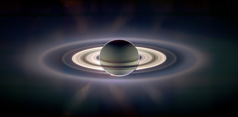 In the shadow of Saturn, unexpected wonders appear. The robotic Cassini spacecraft now orbiting Saturn recently drifted in giant planet's shadow for about 12 hours and looked back toward the eclipsed Sun. Cassini saw a view unlike any other. First, the night side of Saturn is seen to be partly lit by light reflected from its own majestic ring system. Next, the rings themselves appear dark when silhouetted against Saturn, but quite bright when viewed away from Saturn and slightly scattering sunlight, in the above exaggerated color image. Saturn's rings light up so much that new rings were discovered, although they are hard to see in the above image. Visible in spectacular detail, however, is Saturn's E ring, the ring created by the newly discovered ice-fountains of the moon Enceladus, and the outermost ring visible above. Far in the distance, visible on the image left just above the bright main rings, is the almost ignorable pale blue dot of Earth.